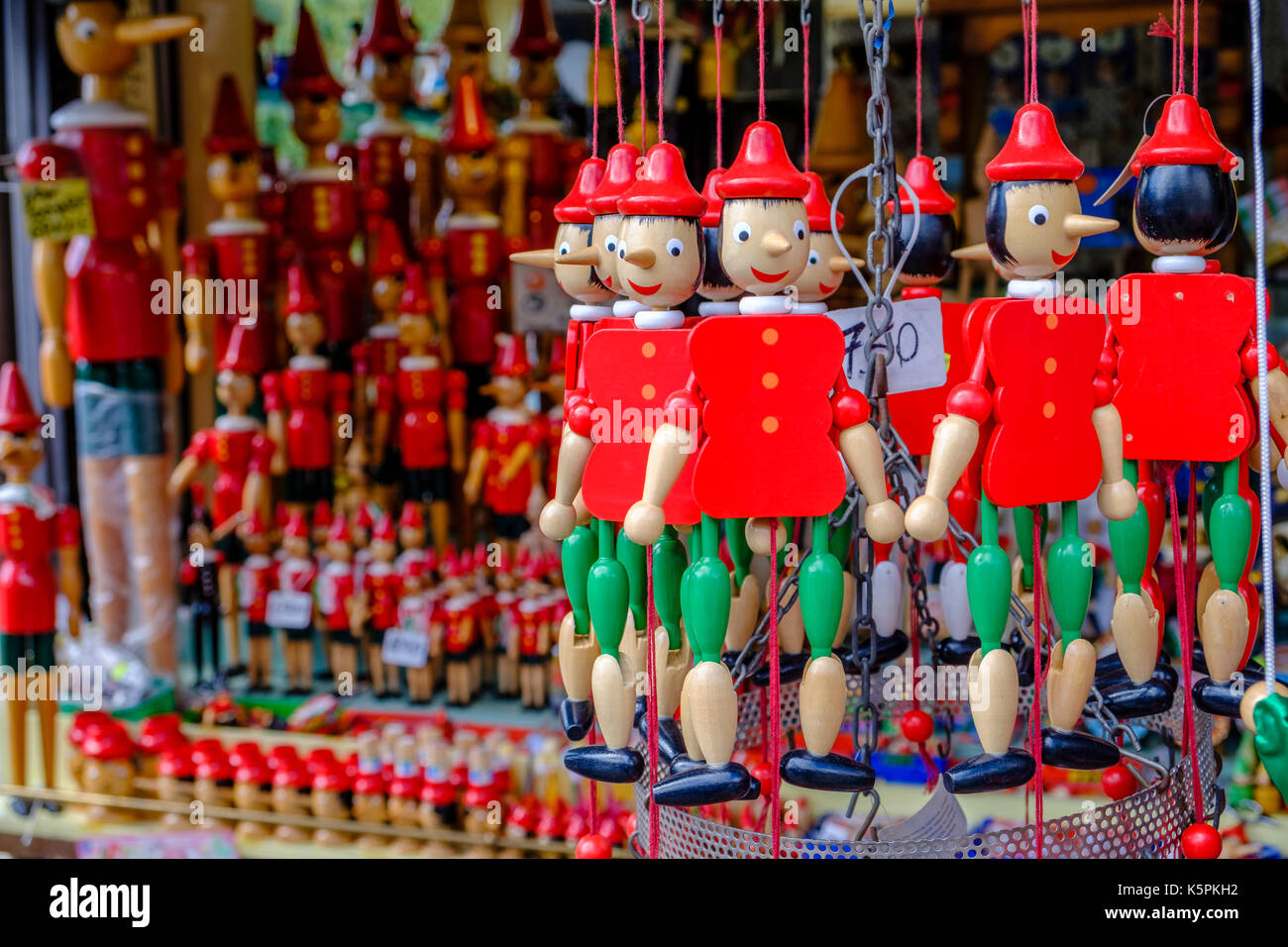 Small colorful woodcarved statues of Pinocchio are for sale as souvenirs Stock Photo