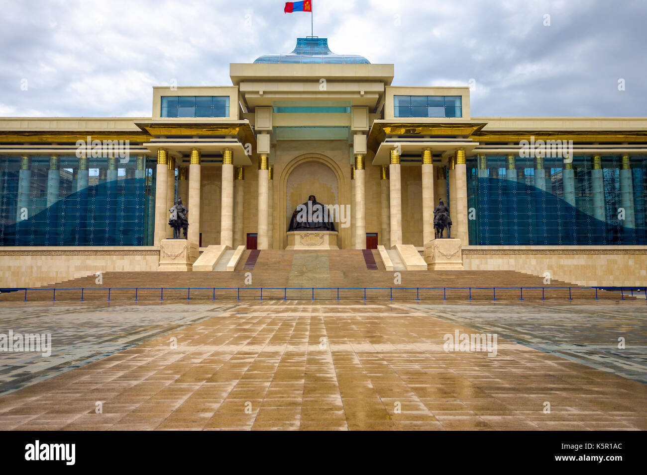 Ghengis Khan statue sits at the center of the Government Palace building on a rainy wet day at Sukhbaatar Square in downtown Ulaanbaatar, Mongolia Stock Photo