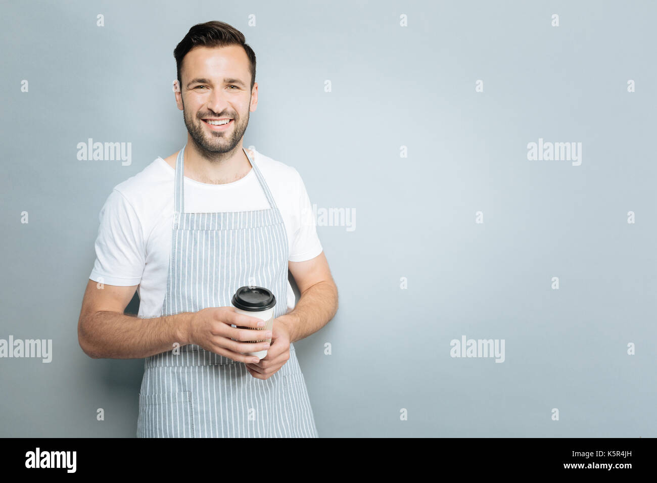 Positive delighted man holding paper cup Stock Photo - Alamy