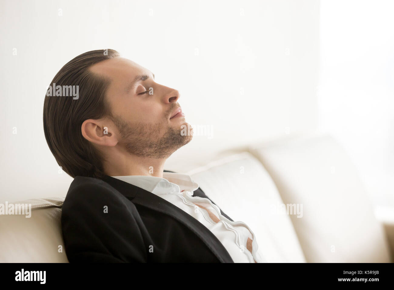 Young man in suit resting or meditating with eyes closed. Stock Photo