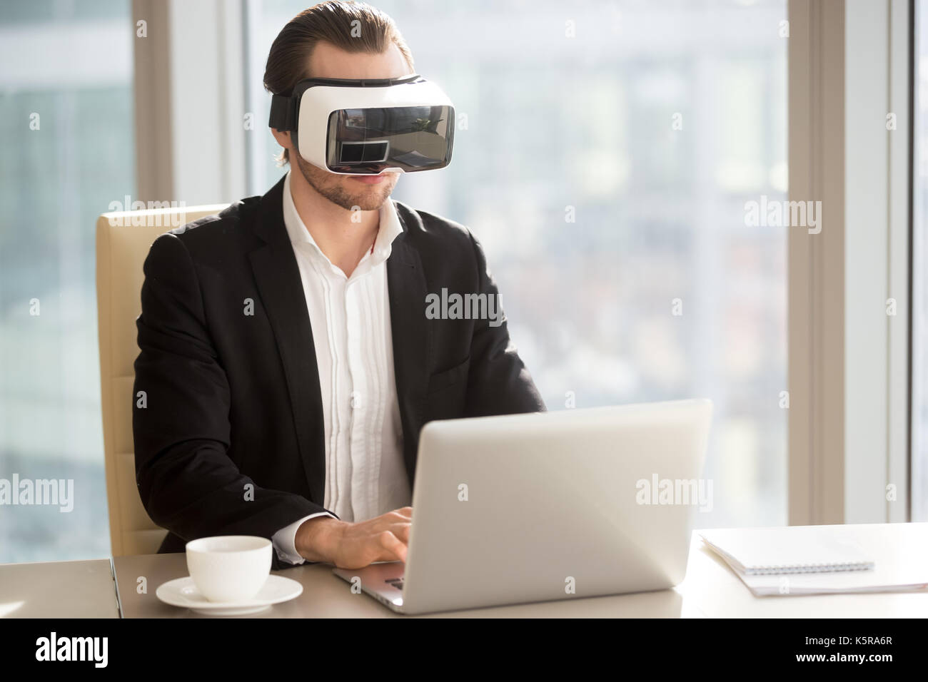 Businessman in VR headset performing application test on compute ...