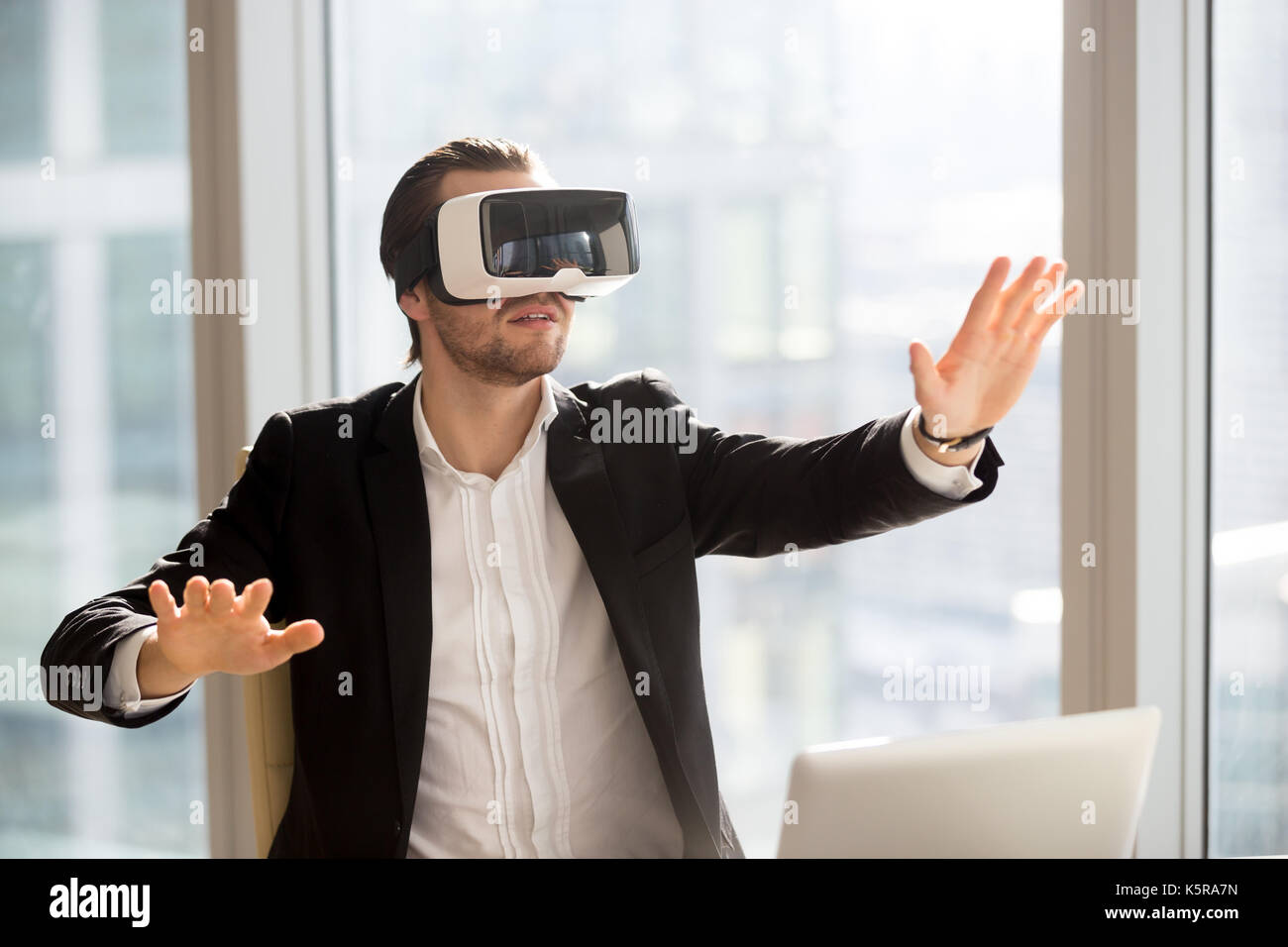 Businessman in vr headset touching air immersed in virtual reali Stock Photo
