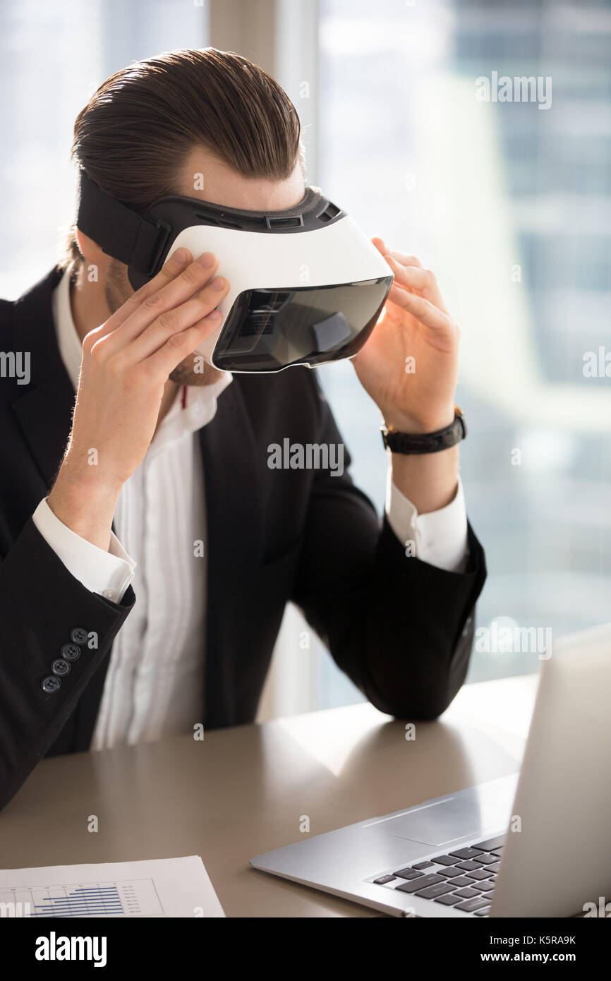 Businessman wears vr glasses looking at laptop screen. Stock Photo
