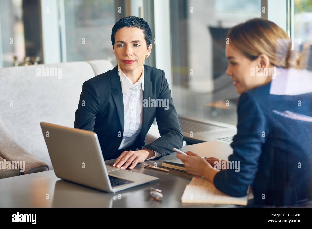 Team of talented managers brainstorming on start-up project while having working meeting at cozy small coffeehouse, view through panoramic window Stock Photo