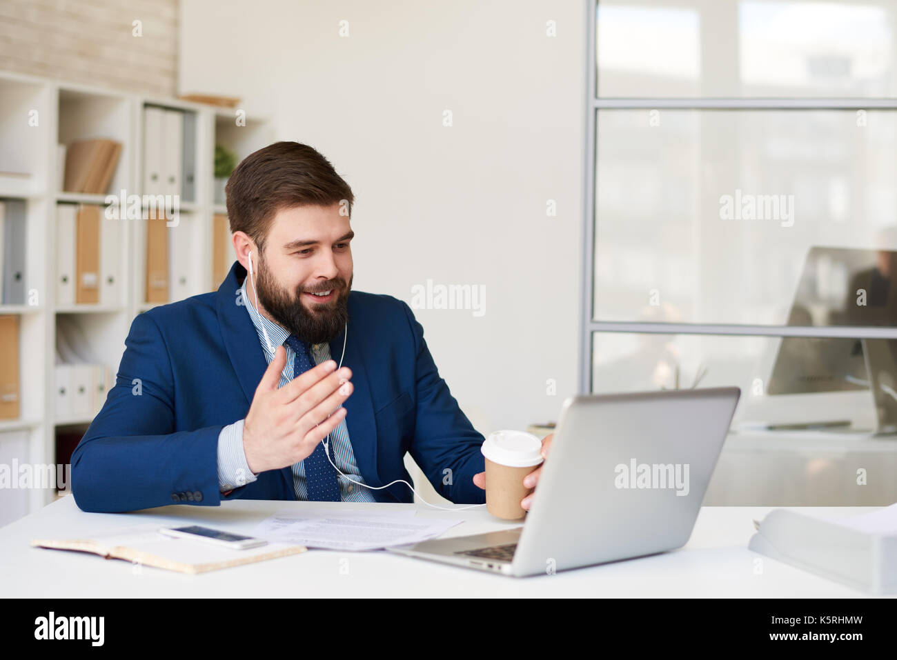 Portrait of smiling bearded businessman speaking with partner via laptop by video chat meeting Stock Photo