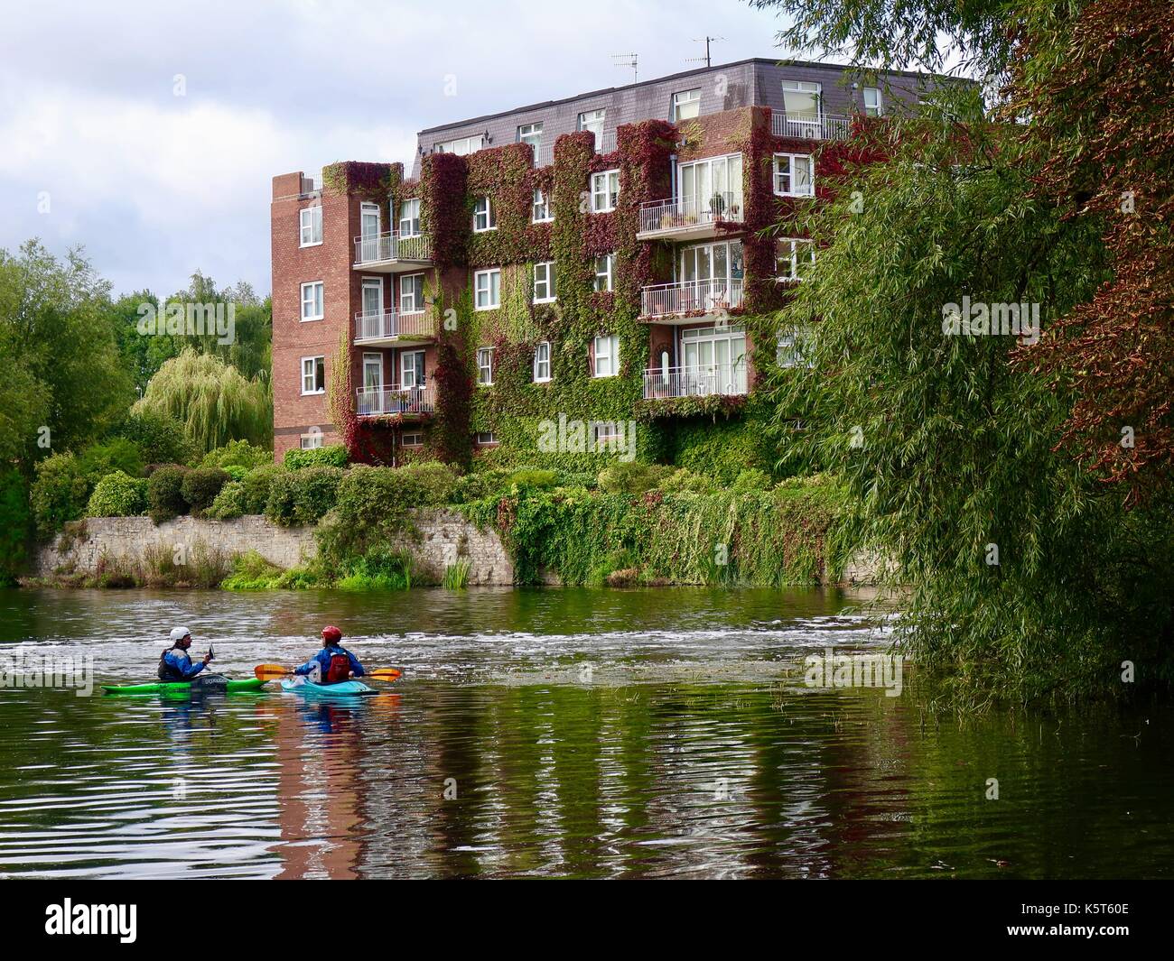 Two canoeists by the Lucy's Mill weir and riverside apartments. River
