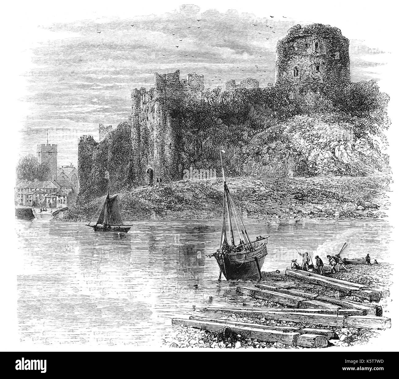1870: Arnulf of Montgomery built the first Pembroke Castle in 1093 when he fortified the promontory beside the Pembroke River during the Norman invasion of Wales. A century later the castle was given to William Marshal who became one of the most powerful men in 12th-century Britain. He rebuilt Pembroke Castle in stone creating most of the structure that remains behind ths small ship repair yard. Pembrokeshire, South Wales. Stock Photo