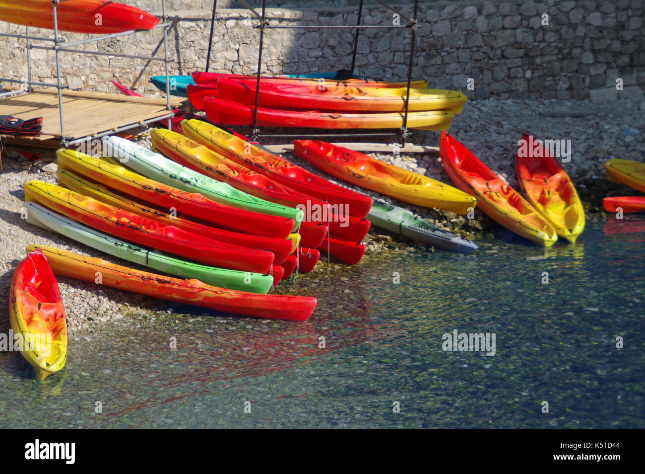 Colorful canoes on water. Red and yellow kayaks ready for summer activities and recreation. Stock Photo