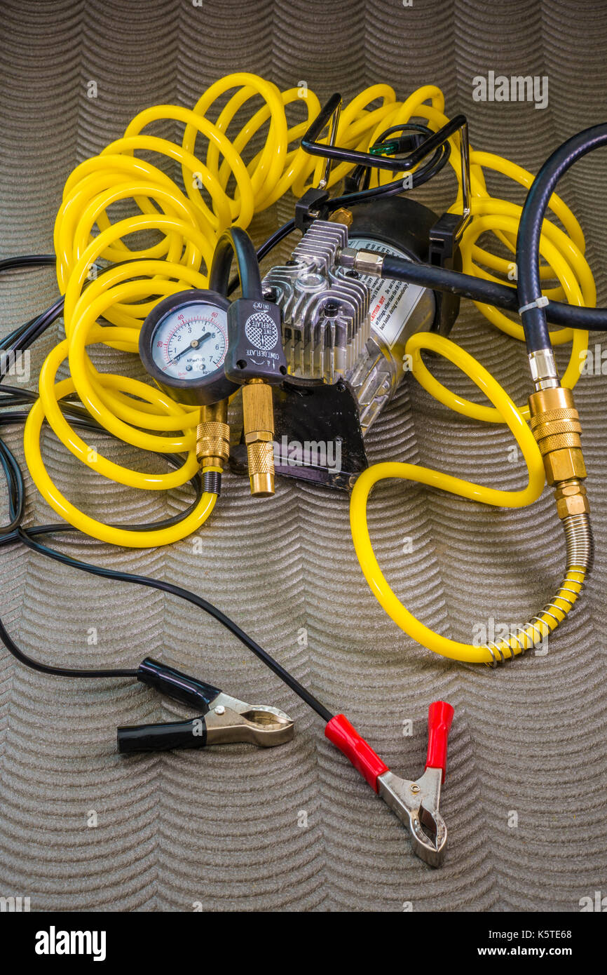 12 volt professional tyre inflator, with compressor, brass fittings, long coiled air hose and crocodile clips for connection to battery terminals. Stock Photo