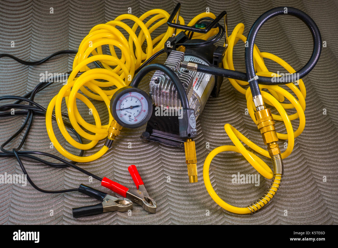 12 volt professional tyre inflator, with compressor, brass fittings, long coiled air hose and crocodile clips for connection to battery terminals. Stock Photo