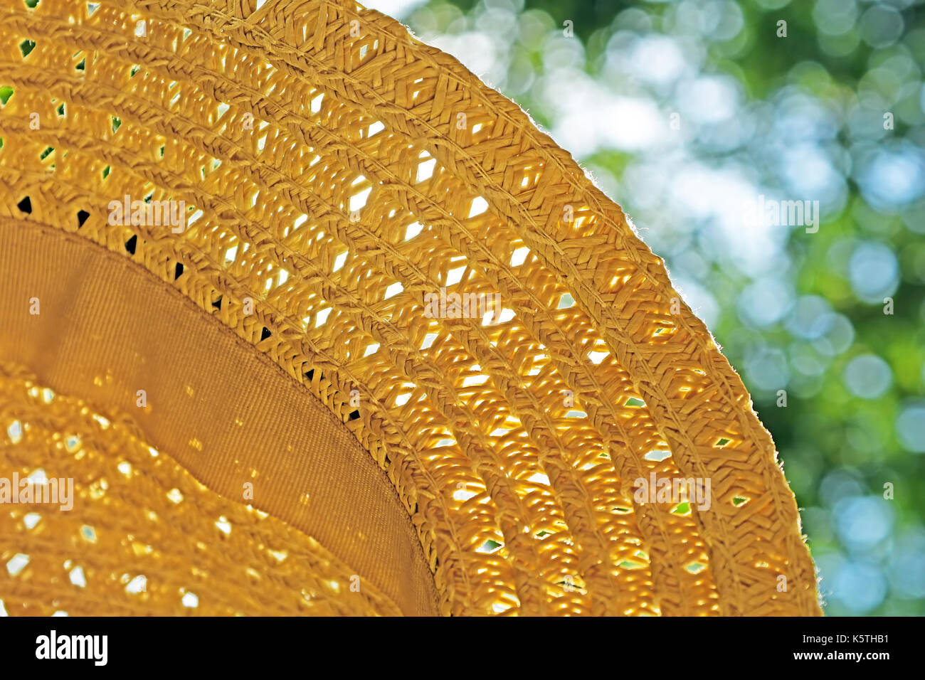 Straw hat and the green foliage as background Stock Photo - Alamy