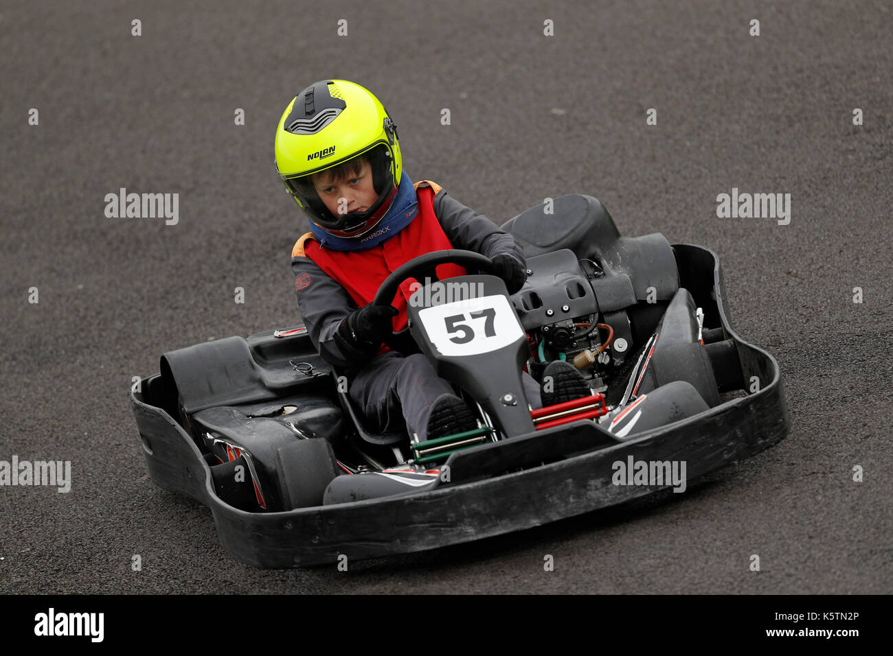 Young boys learn to drive karts on a track during a Junior Karting course at Thruxton racing circuit in Thruxton Hampshire, England Stock Photo