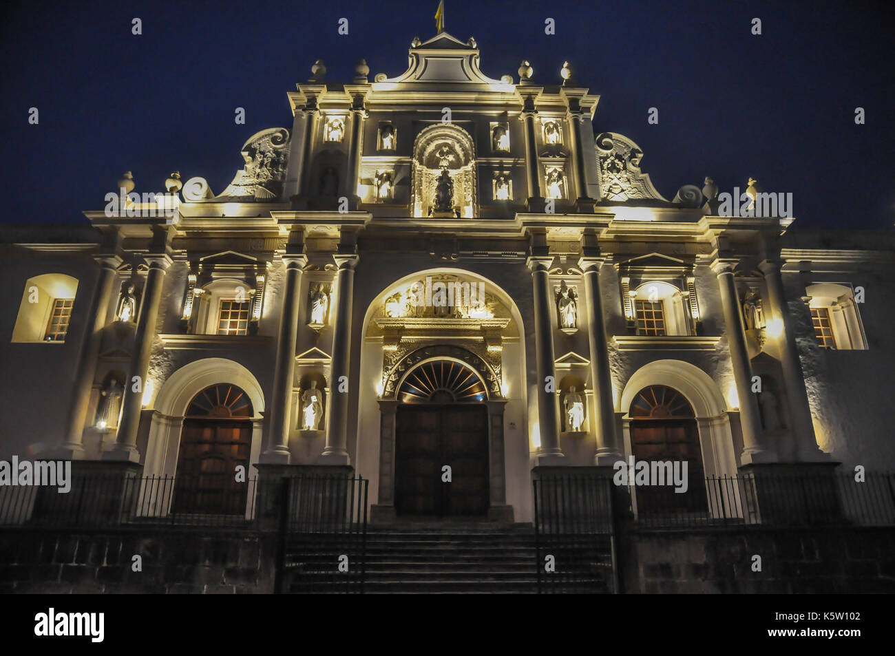 A baroque-style church facade illuminated at night, displaying its intricate architectural details and warm lighting Antigua guatemala Stock Photo