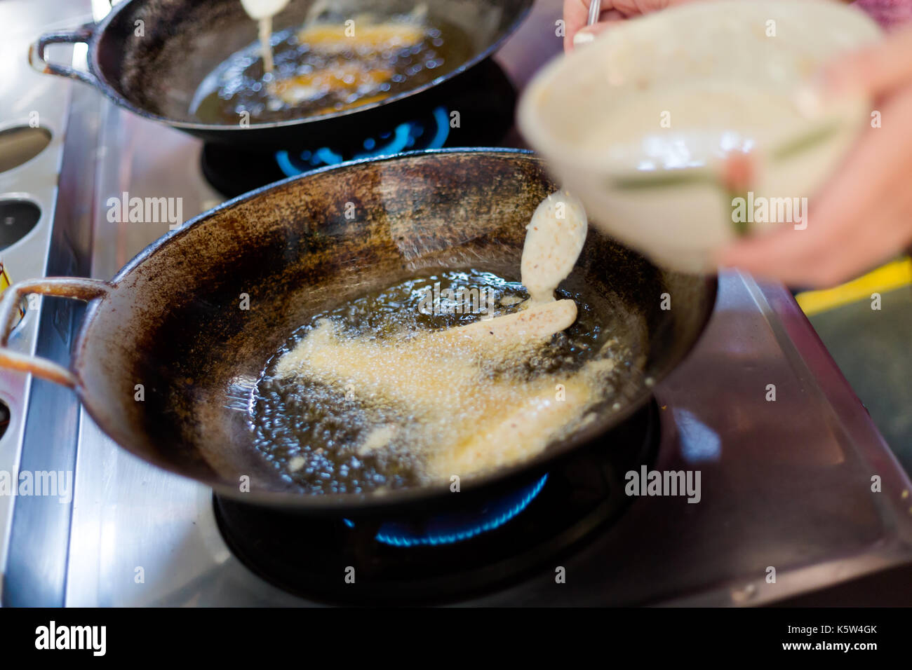 Deep frying battered in rice flour dough banana slices. Picture of
