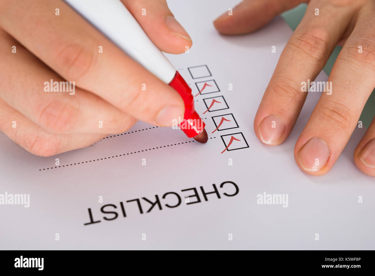 Close-up Of Person Hand Marking On Checklist Form With Red Marker Stock Photo