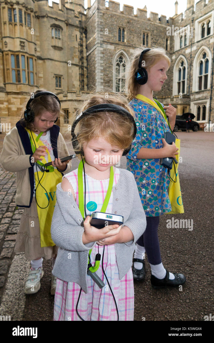 Three sisters /children /kid /kids on holiday listen to an audio guide information while on a tour. Windsor. Berkshire UK. Stock Photo