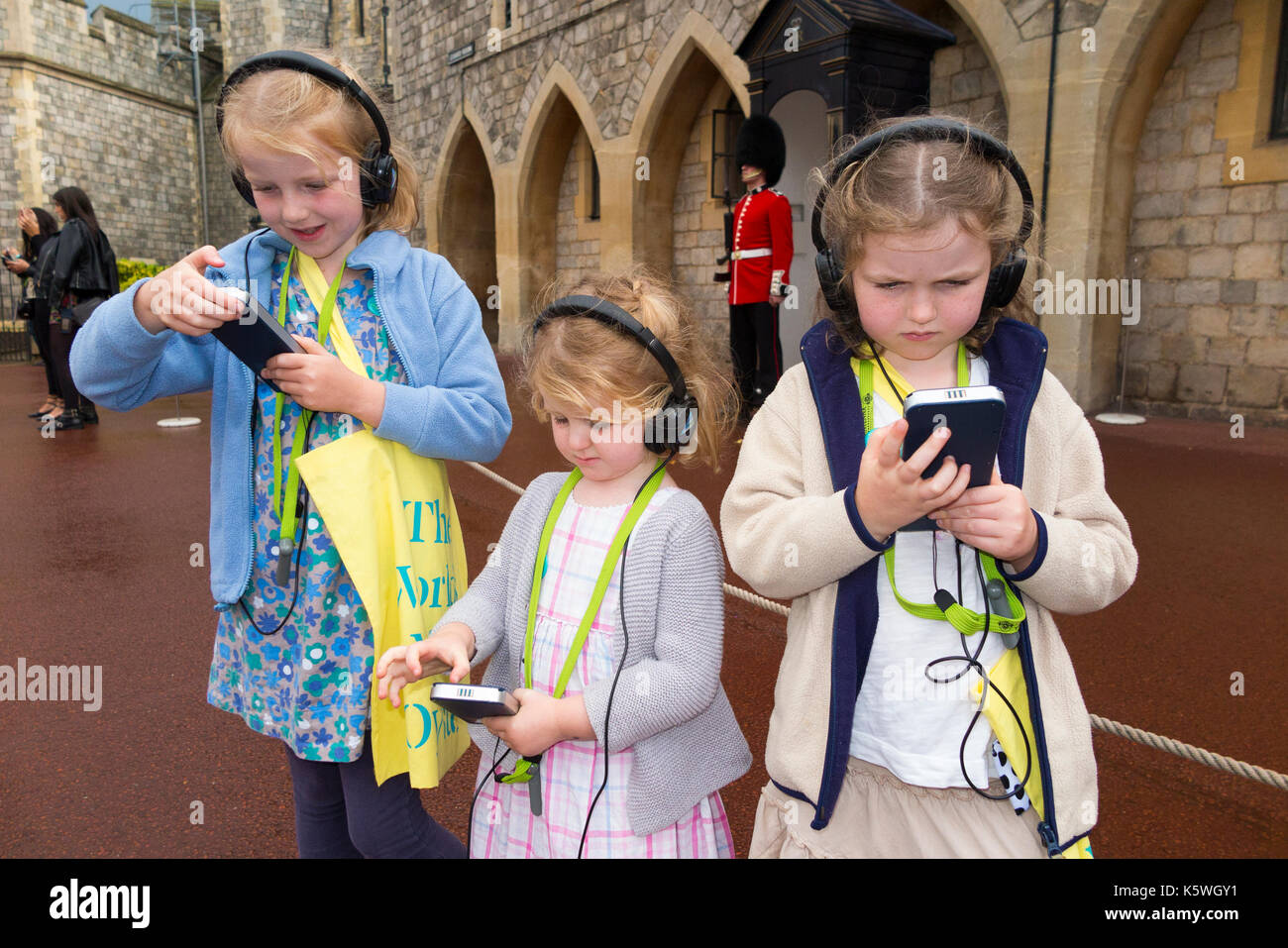 Three sisters /children /kid /kids on holiday listen to an audio guide information while on a tour. Windsor. Berkshire UK. Stock Photo