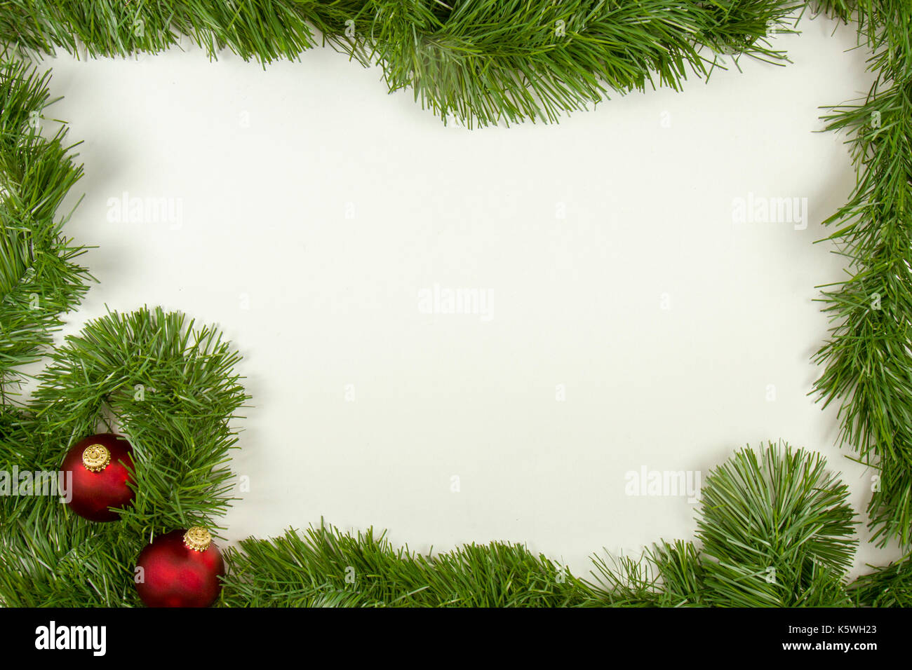 Green garland border with red ornament balls framing white copy space