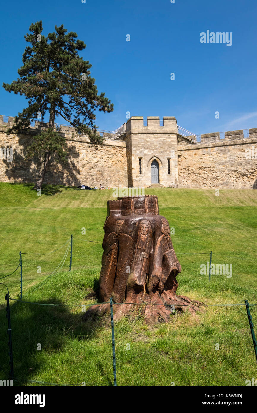 Tree trunk carved with medieval knights and figures in the grounds of Lincoln castle, City of Lincoln, Lincolnshire, England, UK Stock Photo