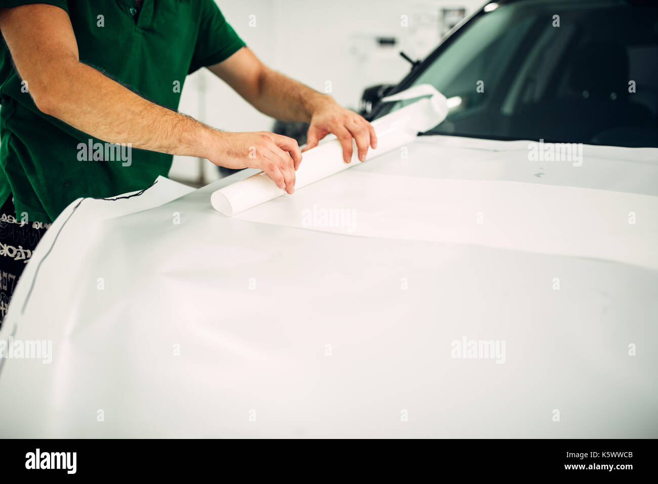 Professional automobile paint protection film installation process. Worker hands prepares