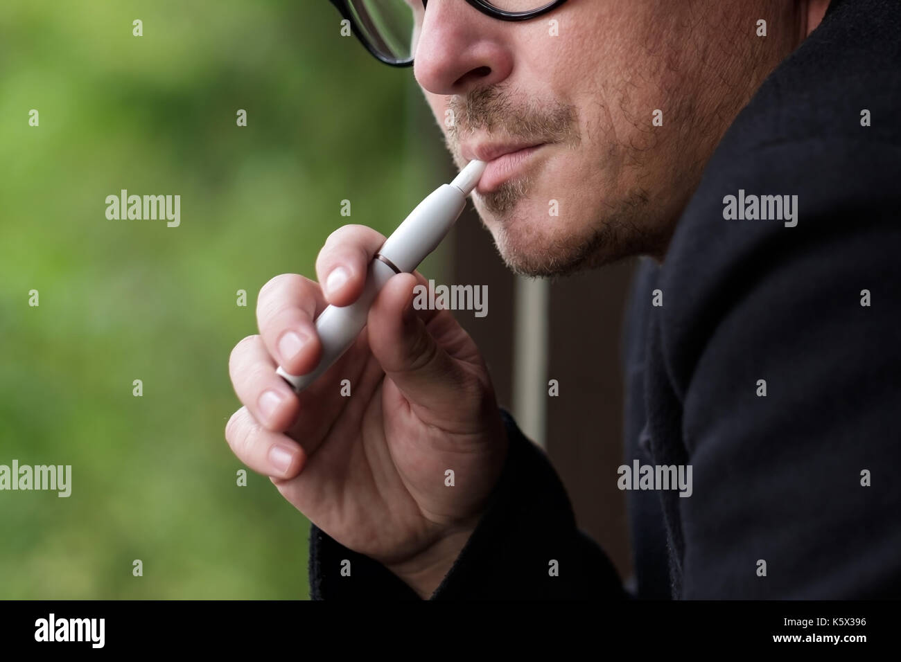 Caucasian man smoking modern hybrid cigarette device outdoor Stock Photo