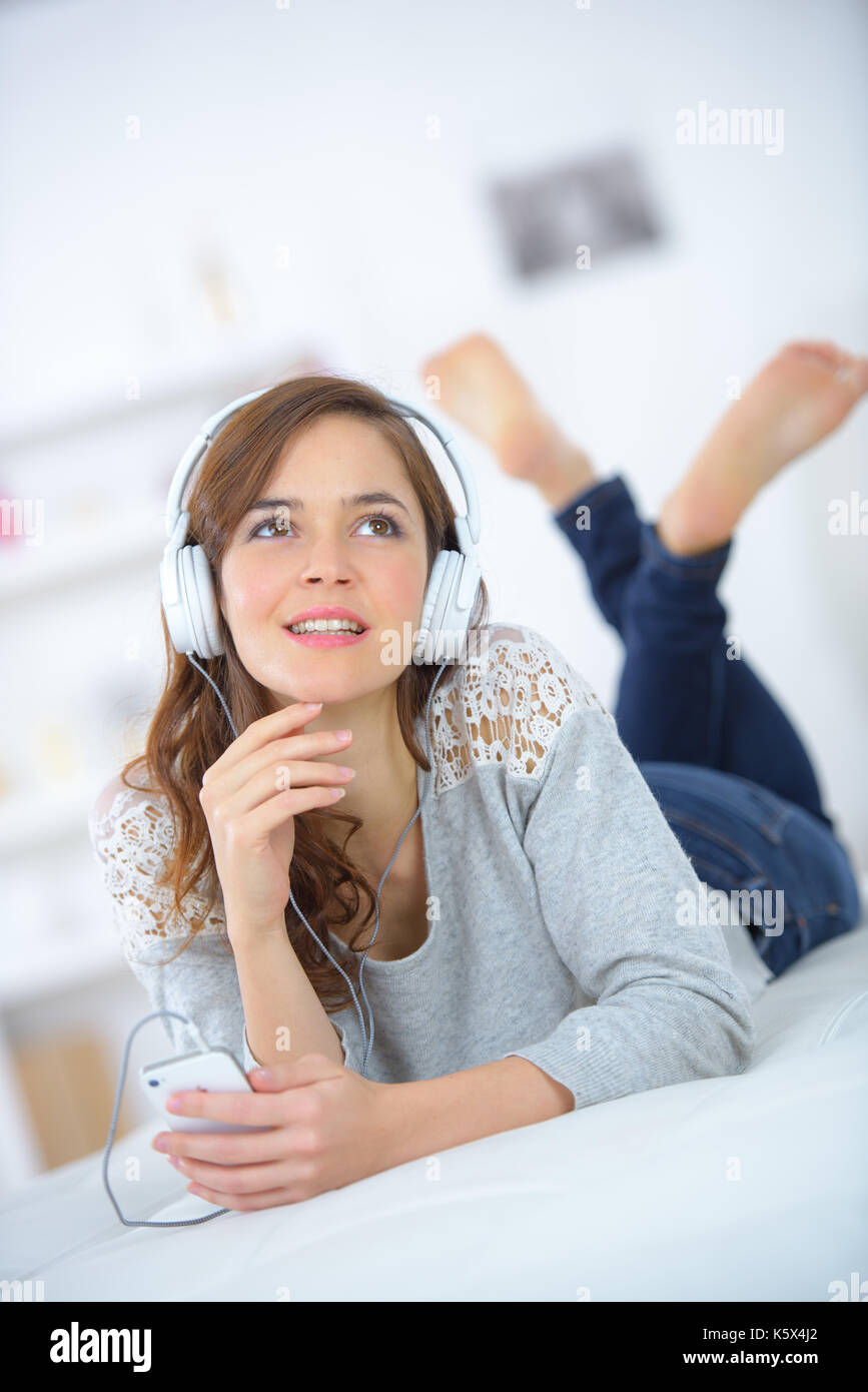 young female lying on bed and listening to music Stock Photo - Alamy