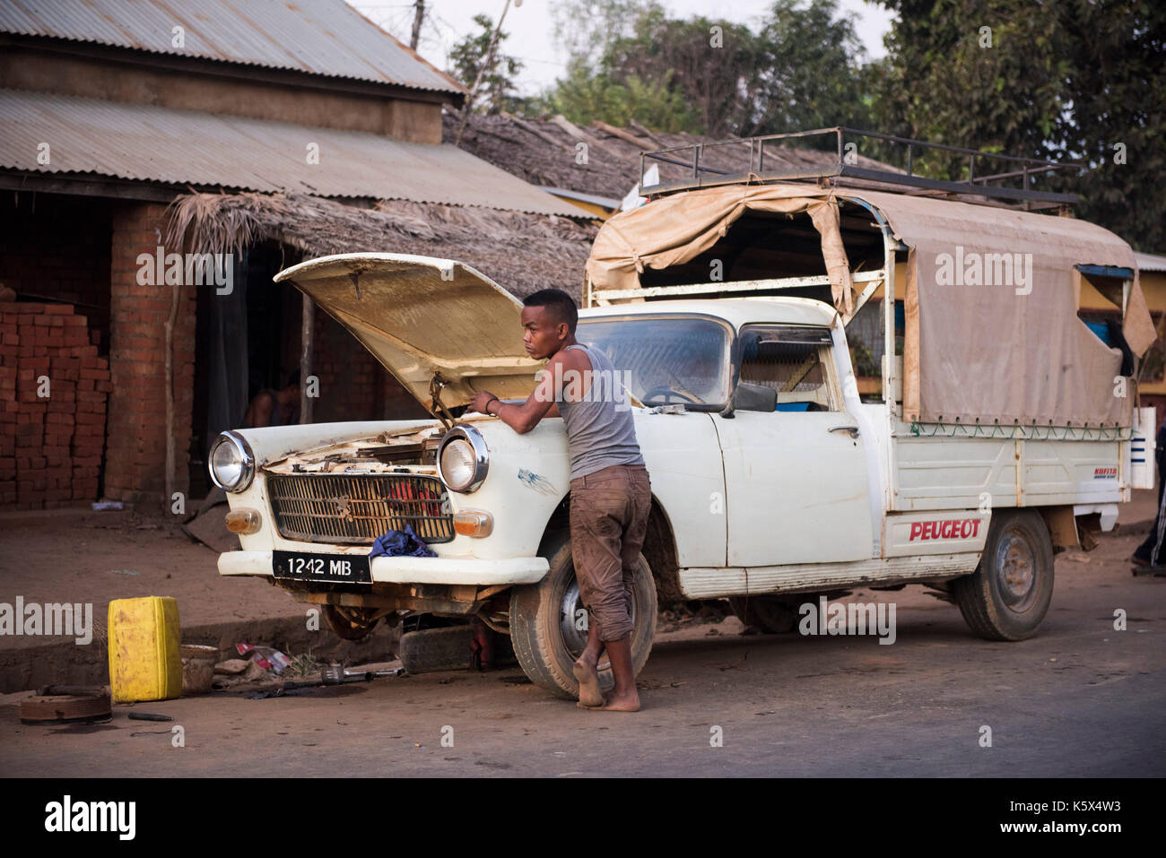 Young mechanic working on old Peugeot car, Andranofasika, Madagascar Stock Photo