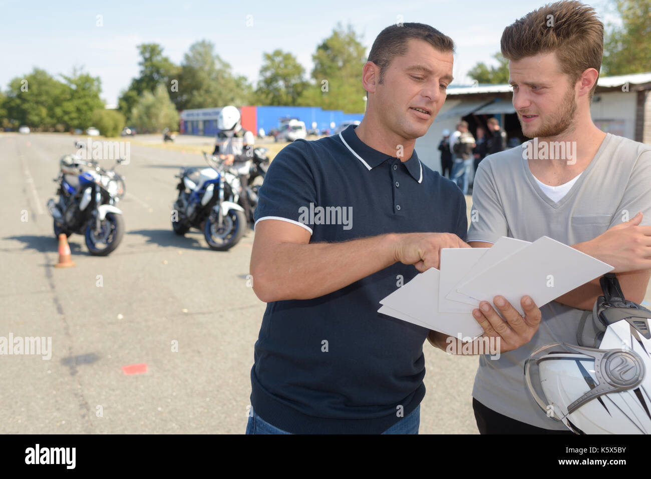 driving instructor talks to student before motorbike license test Stock Photo