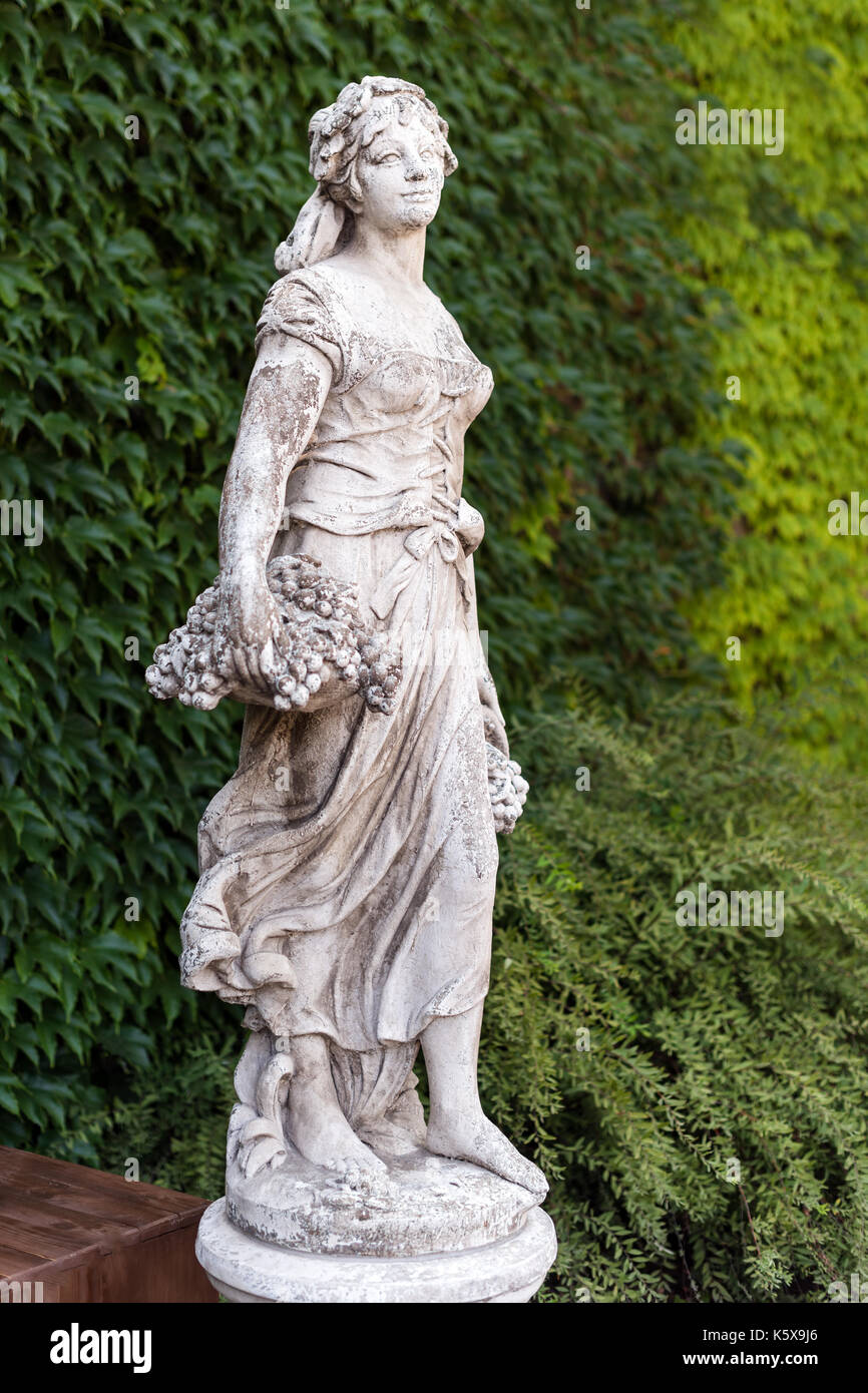 Old marble statue woman with basket of grapes in the park Stock Photo