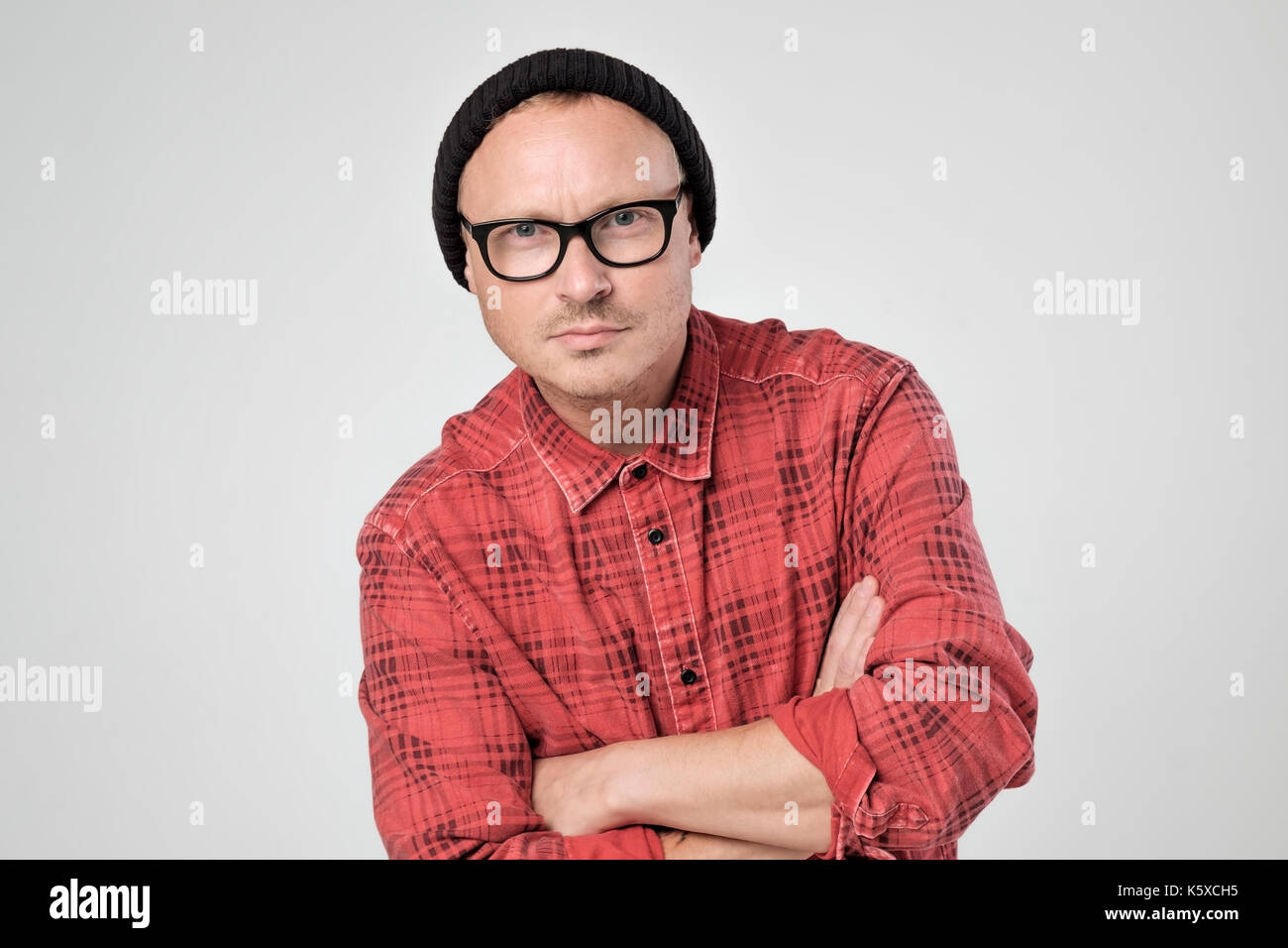 Smiling young man in red shirt standing against white background Stock Photo