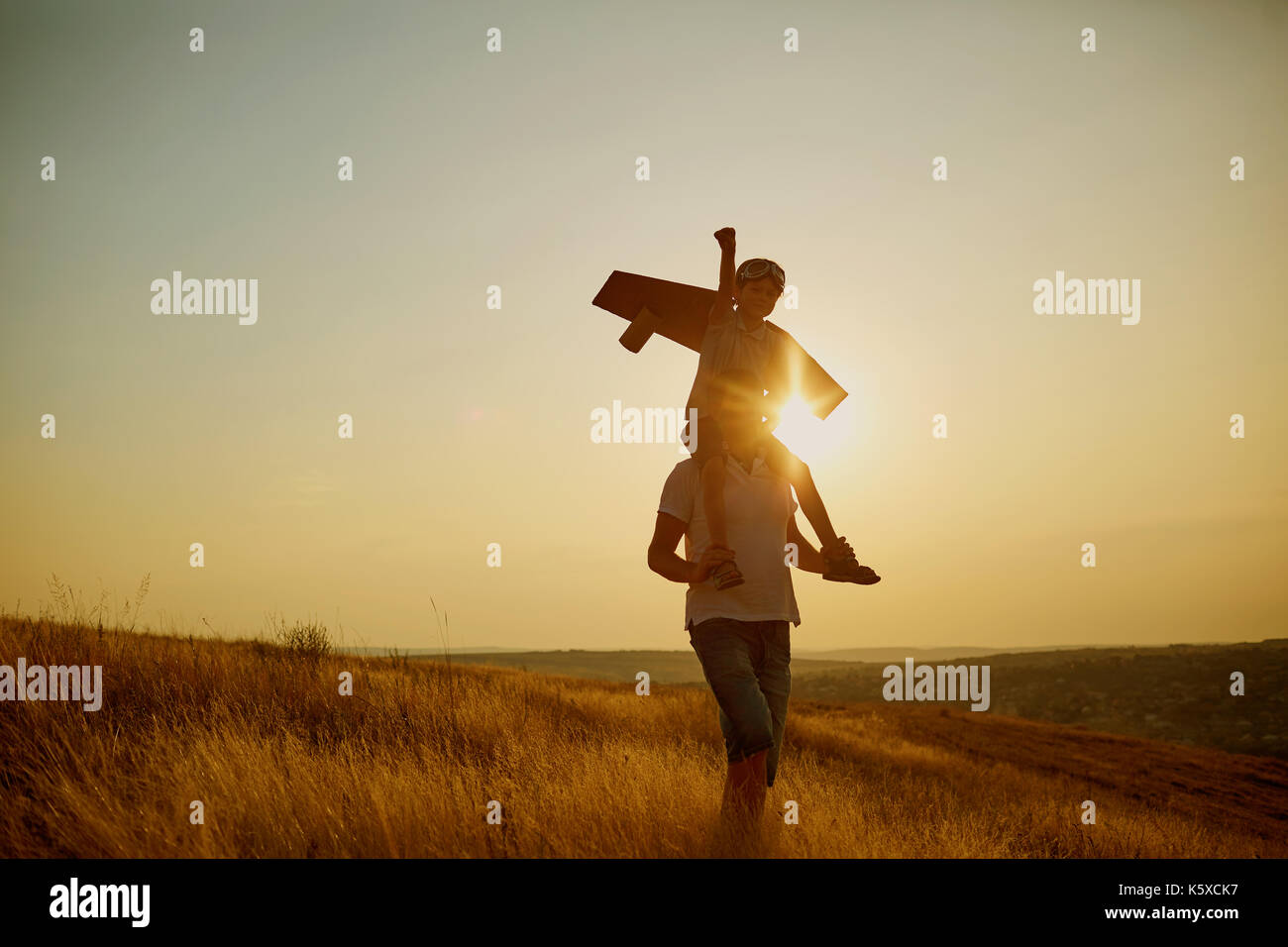 Dad with his son in a pilot's suit at sunset in nature.  Stock Photo