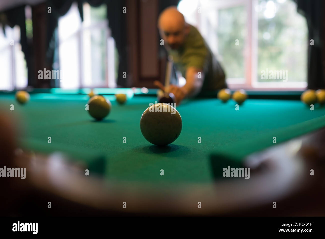 Young man playing billiard indoors. Spending free time on gambling Stock Photo
