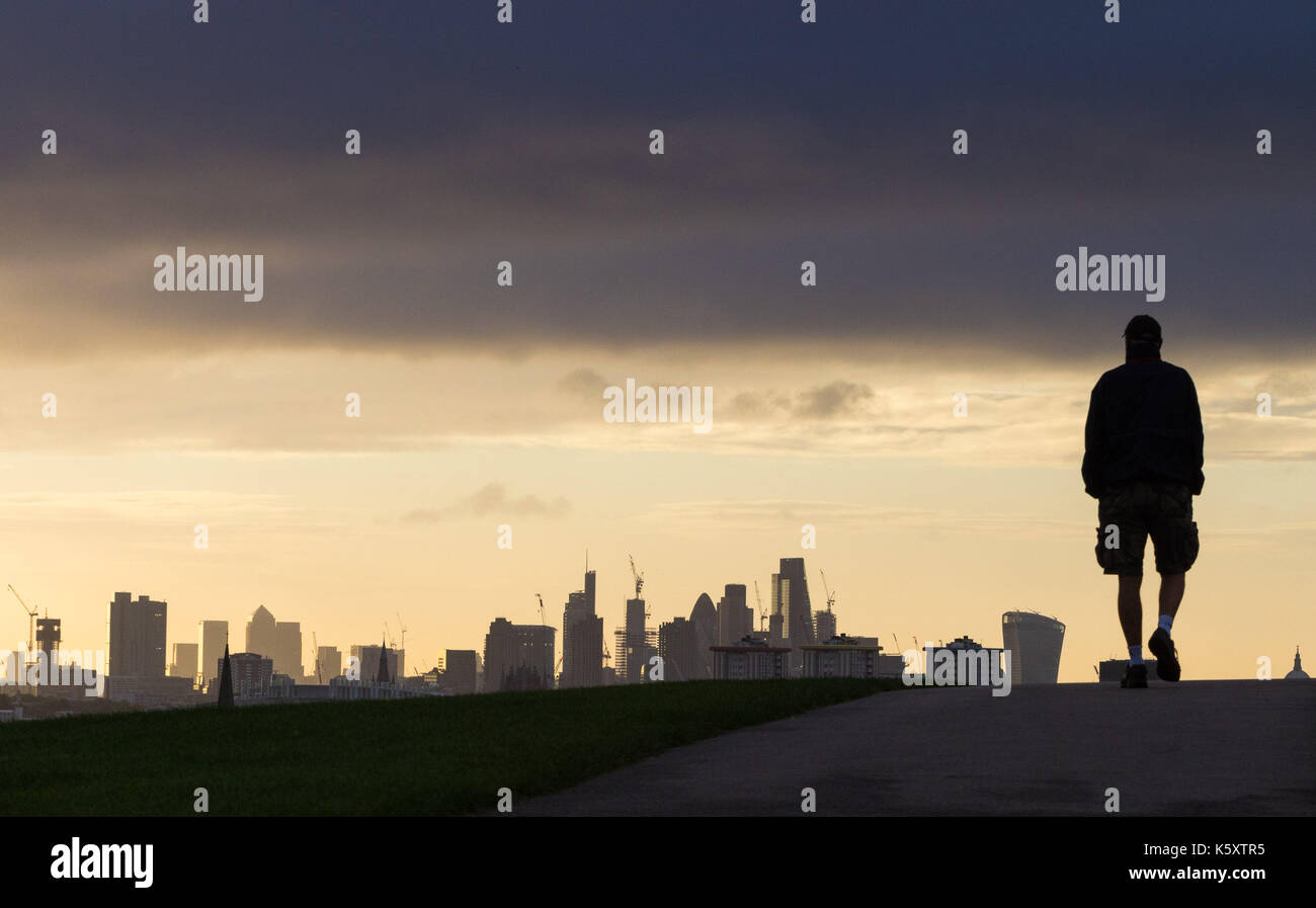 London, UK. 11th Sep, 2017. London, September 11 2017. A walker's figure is thrown into silhouette against the London skyline, seen from Primrose Hill, as a new day breaks over the city. Credit: Paul Davey/Alamy Live News Stock Photo