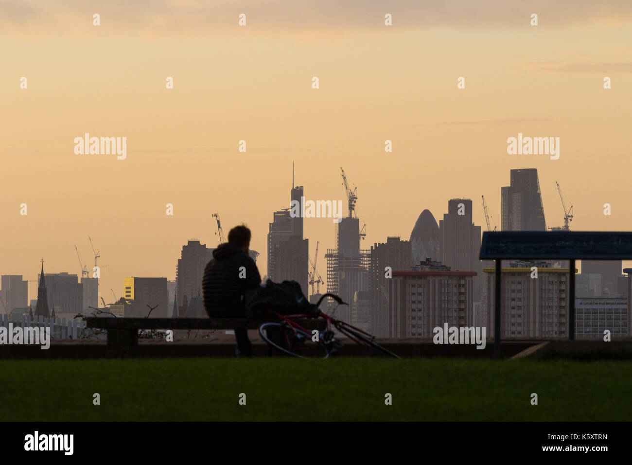 London, UK. 11th Sep, 2017. London, September 11 2017. A cyclist pauses to admire the London skyline as a new day breaks over the city. Credit: Paul Davey/Alamy Live News Stock Photo