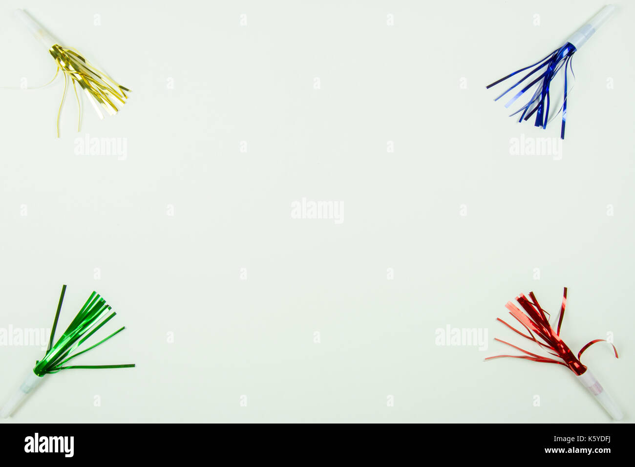 Red, green, gold and blue party noise makers with streamers on white