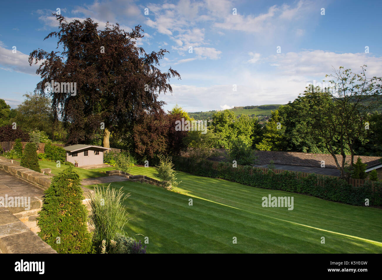 Beautiful, private, traditional, landscaped, country garden, West Yorkshire, England, UK - view over terraced lawns, trees & shed to hillside beyond. Stock Photo