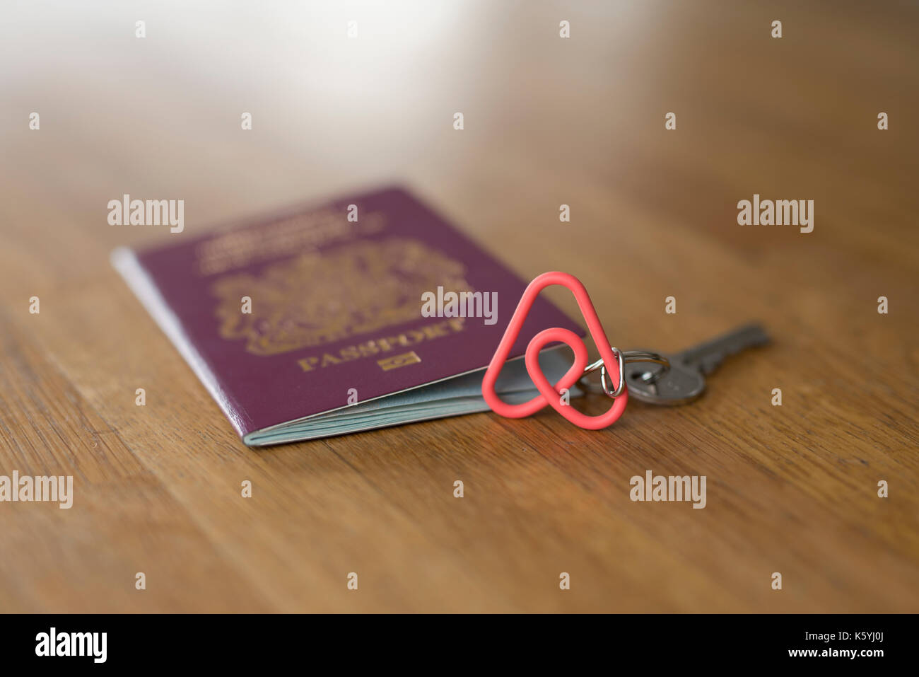 An Airbnb branded keyring along with a British passport on a wooden table  top Stock Photo - Alamy
