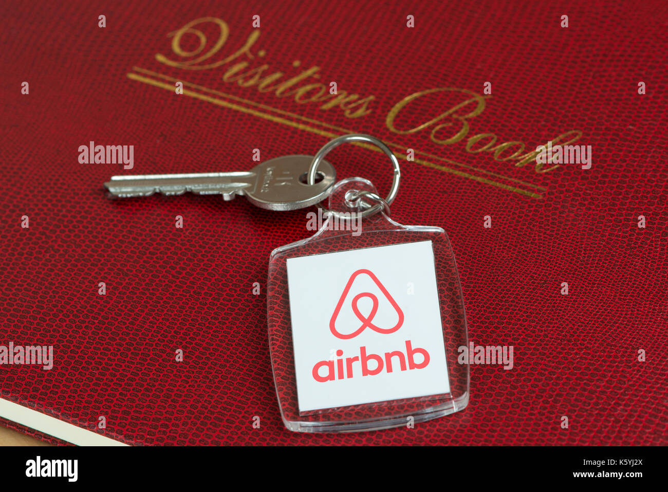 A keyring featuring the Airbnb Belo logo rests on a guests' Visitors book in an apartment available to rent. Stock Photo
