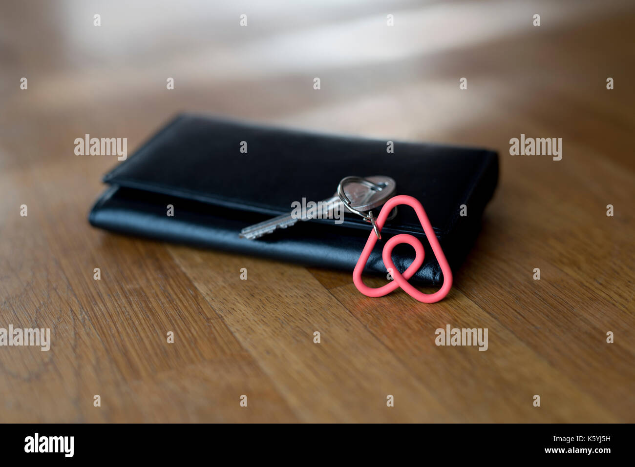 An Airbnb keyring rests against a wallet on the table top of an Airbnb apartment available to hire by guests. Stock Photo