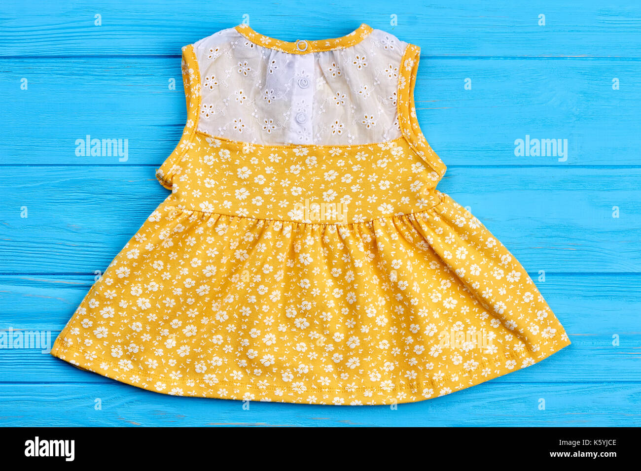 Baby yellow dress with pattern of flowers. Cute colored summer dress