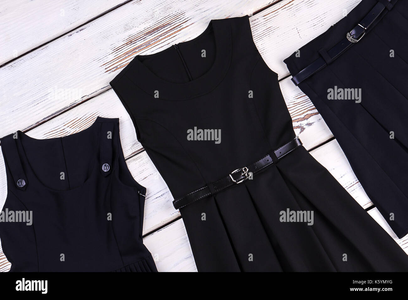 Black school apparel for girls. Girls school belted skater dress, skirt, old wooden background. Stock Photo