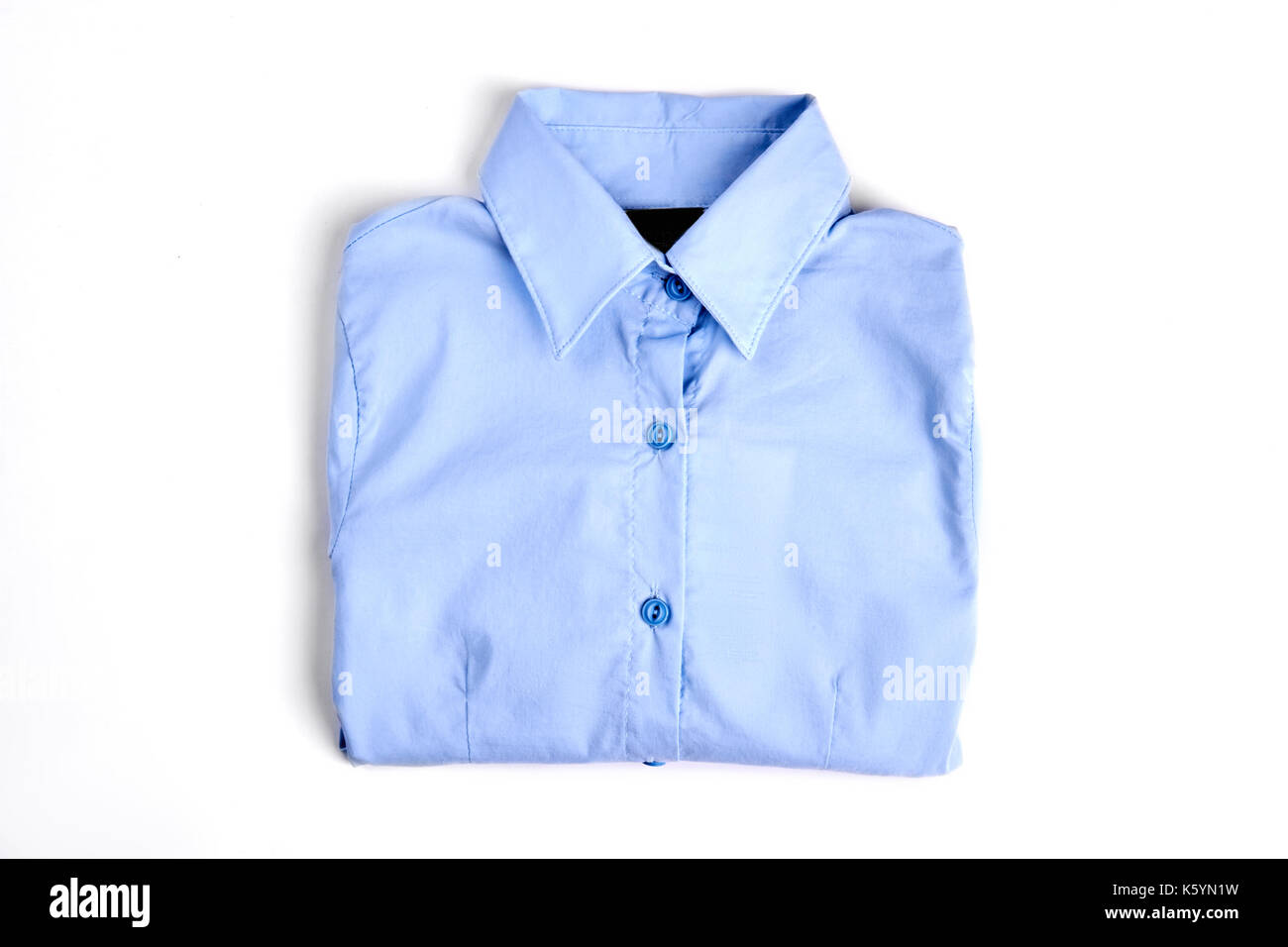 Female light blue formal shirt. New folded cotton woman shirt, white background. Beautiful girls buttoned blouse on sale. Stock Photo