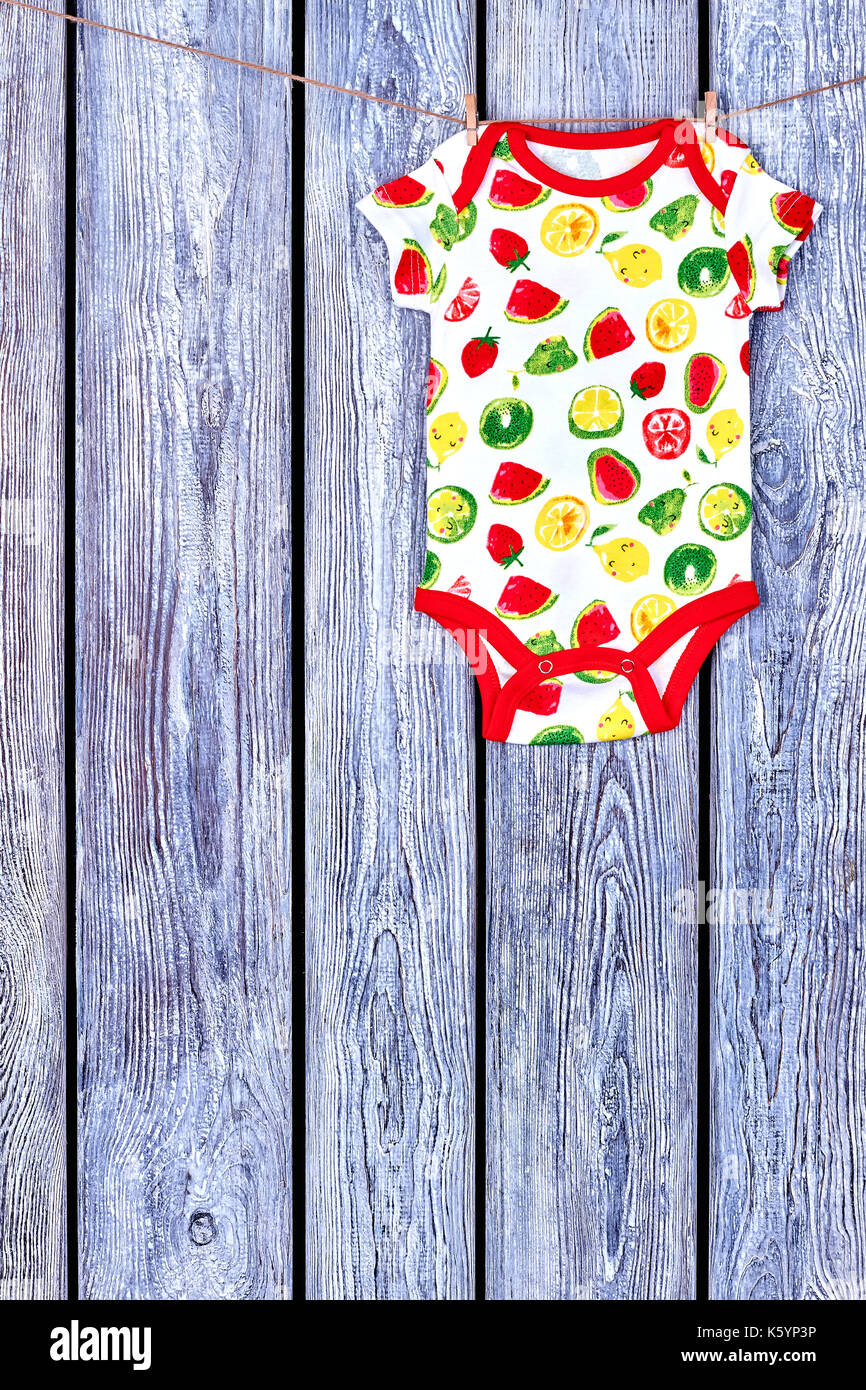 Baby soft bodysuit hanging on clothesline. Rope with drying newborn