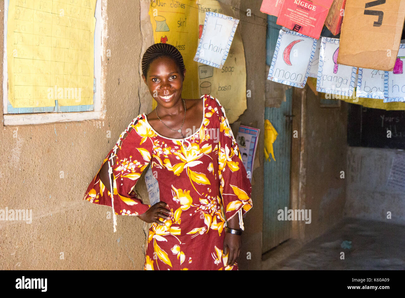 A black Ugandan female teacher smiling. She is in a primary school classroom. Stock Photo