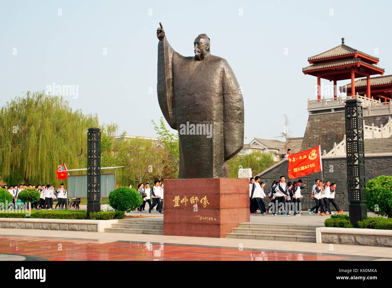 Dongzi Culture Park, City of Dezhou, China. College students parade past statue of Confucian philosopher Dong Zhongshu Stock Photo