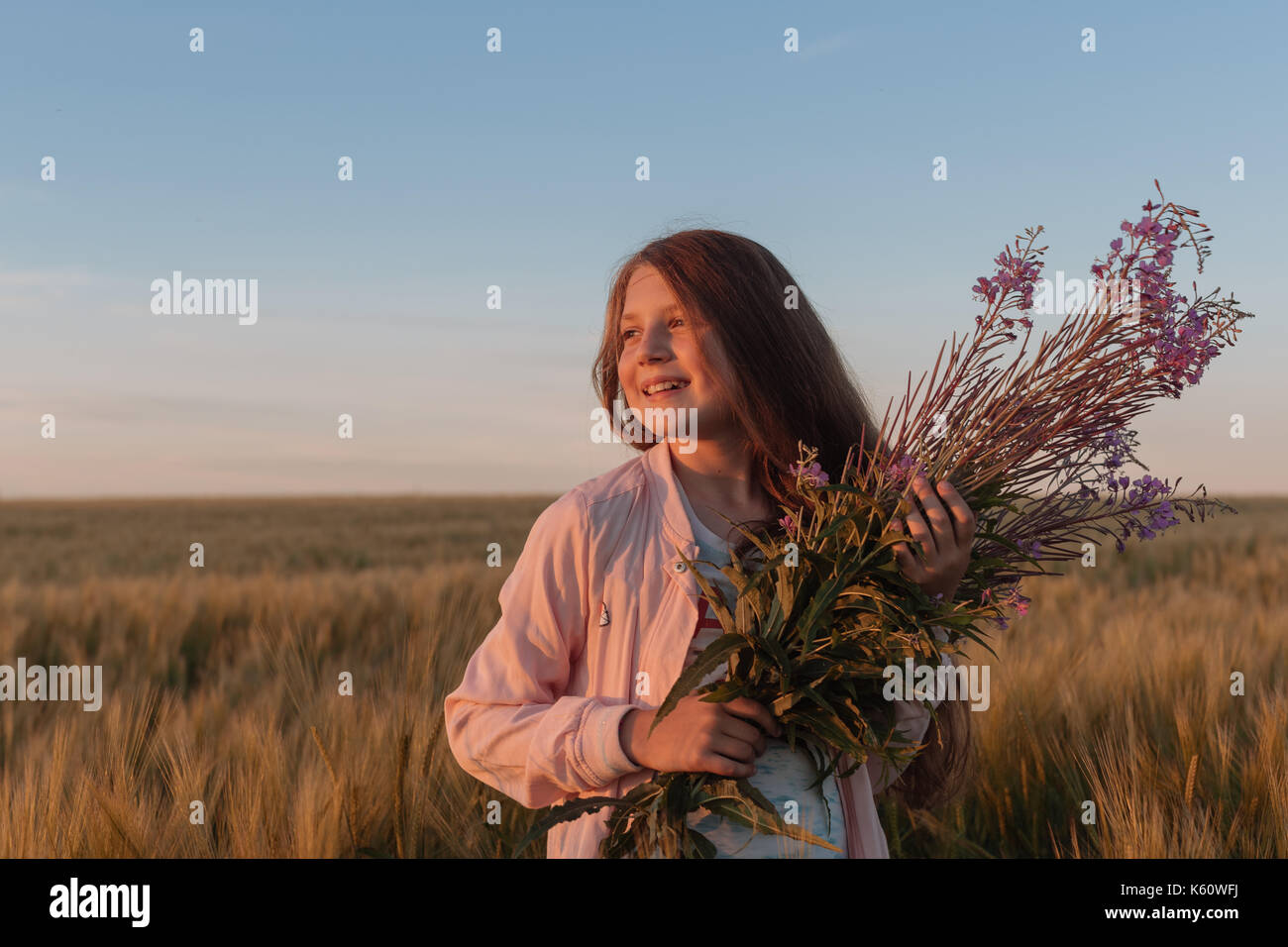 Teen girl in a field with flowers Stock Photo - Alamy