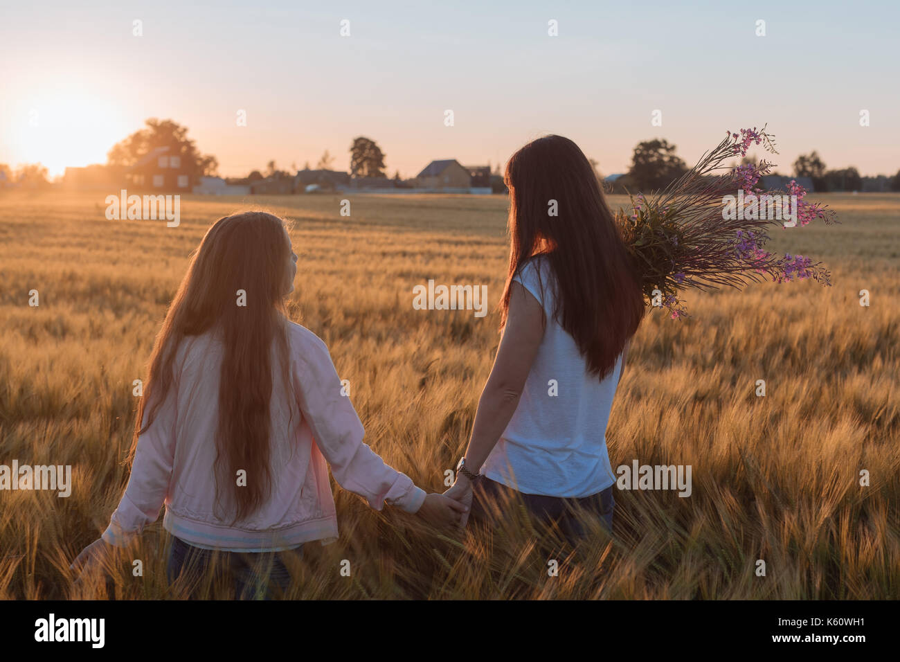 Mom and daughter hold hands and step on the yellow field Stock Photo ...