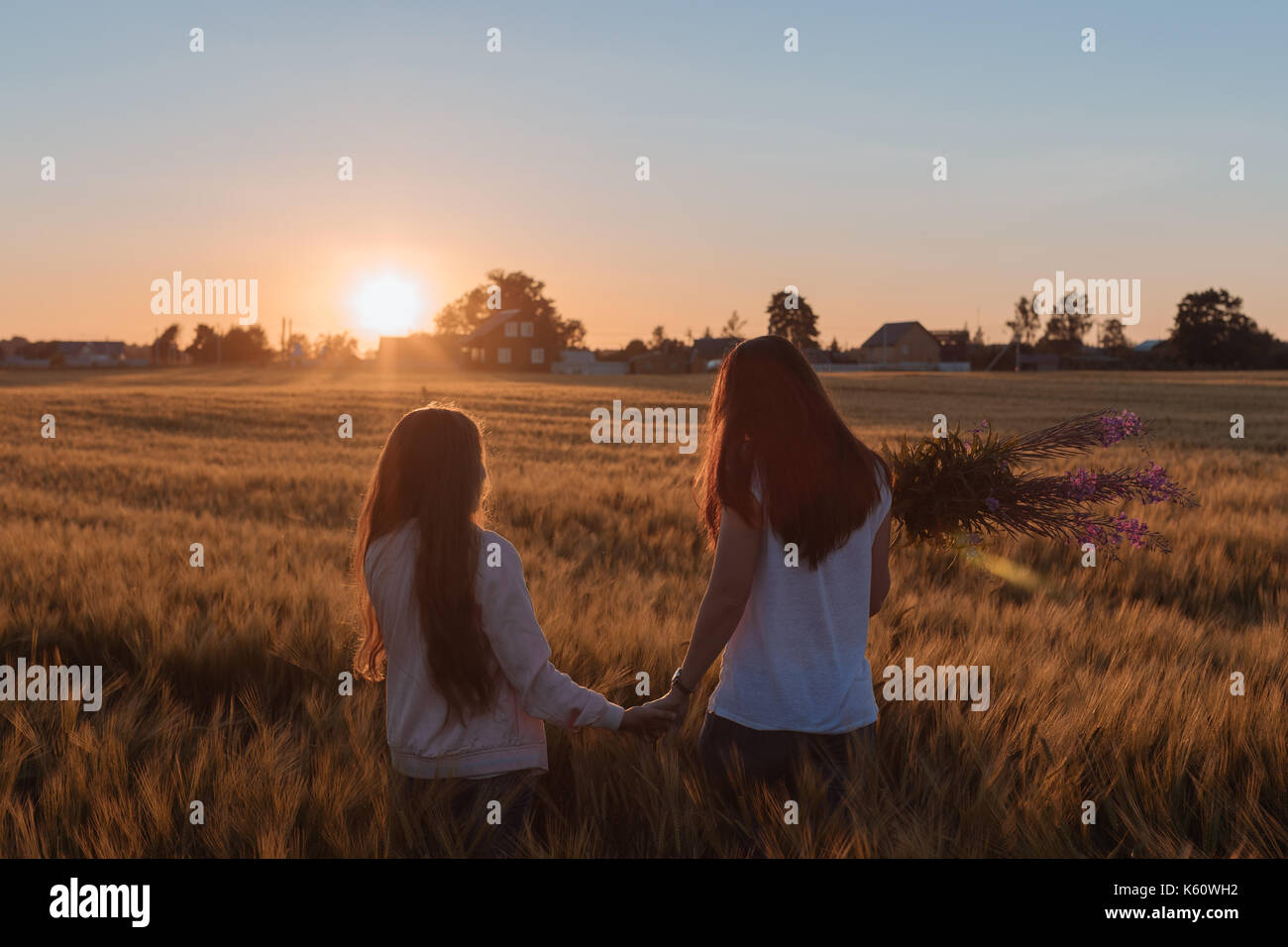 Mom and daughter hold hands and step on the yellow field. Stock Photo