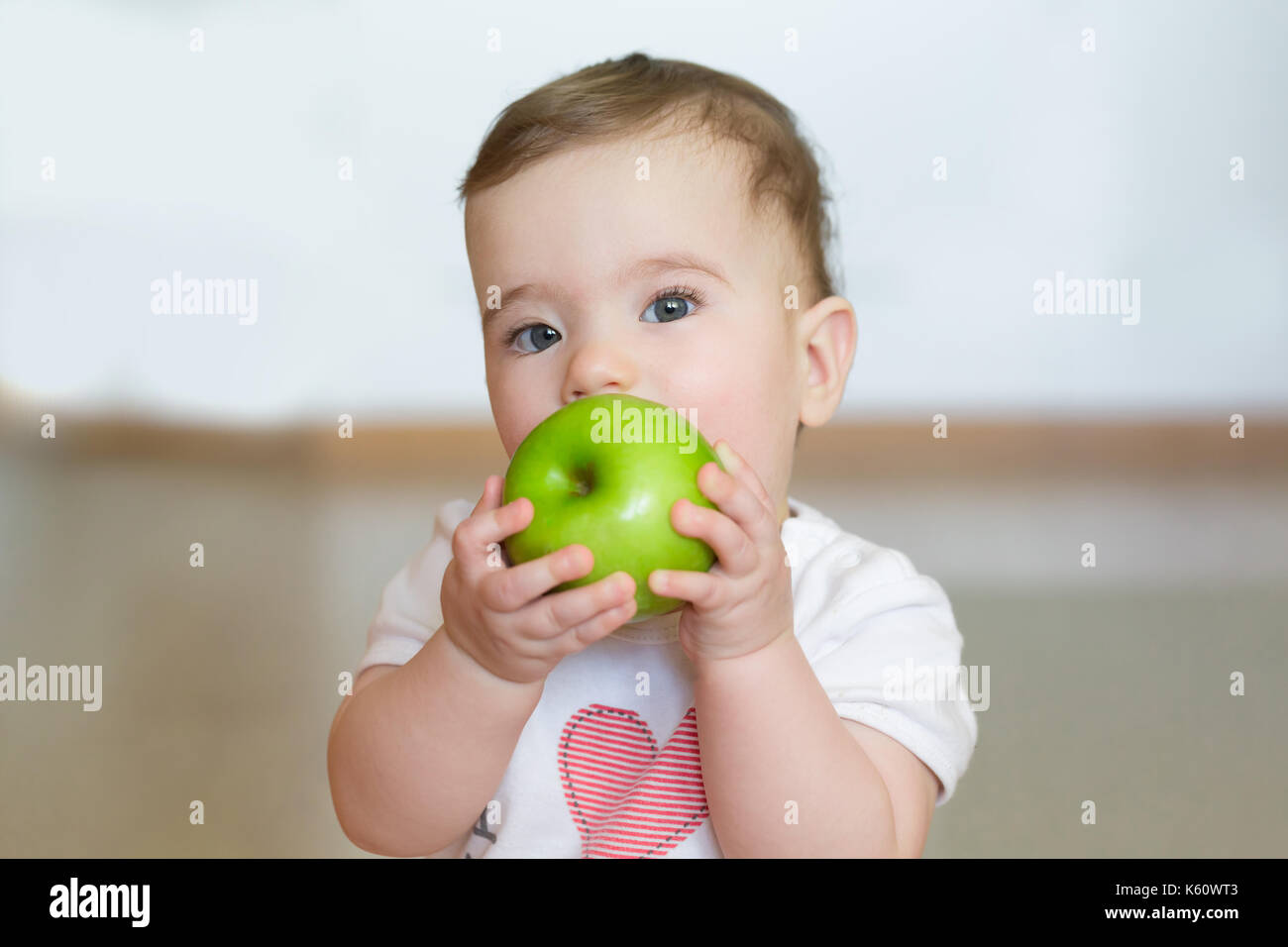 Little child with a green apple in his hands. Close up portrait. Stock Photo