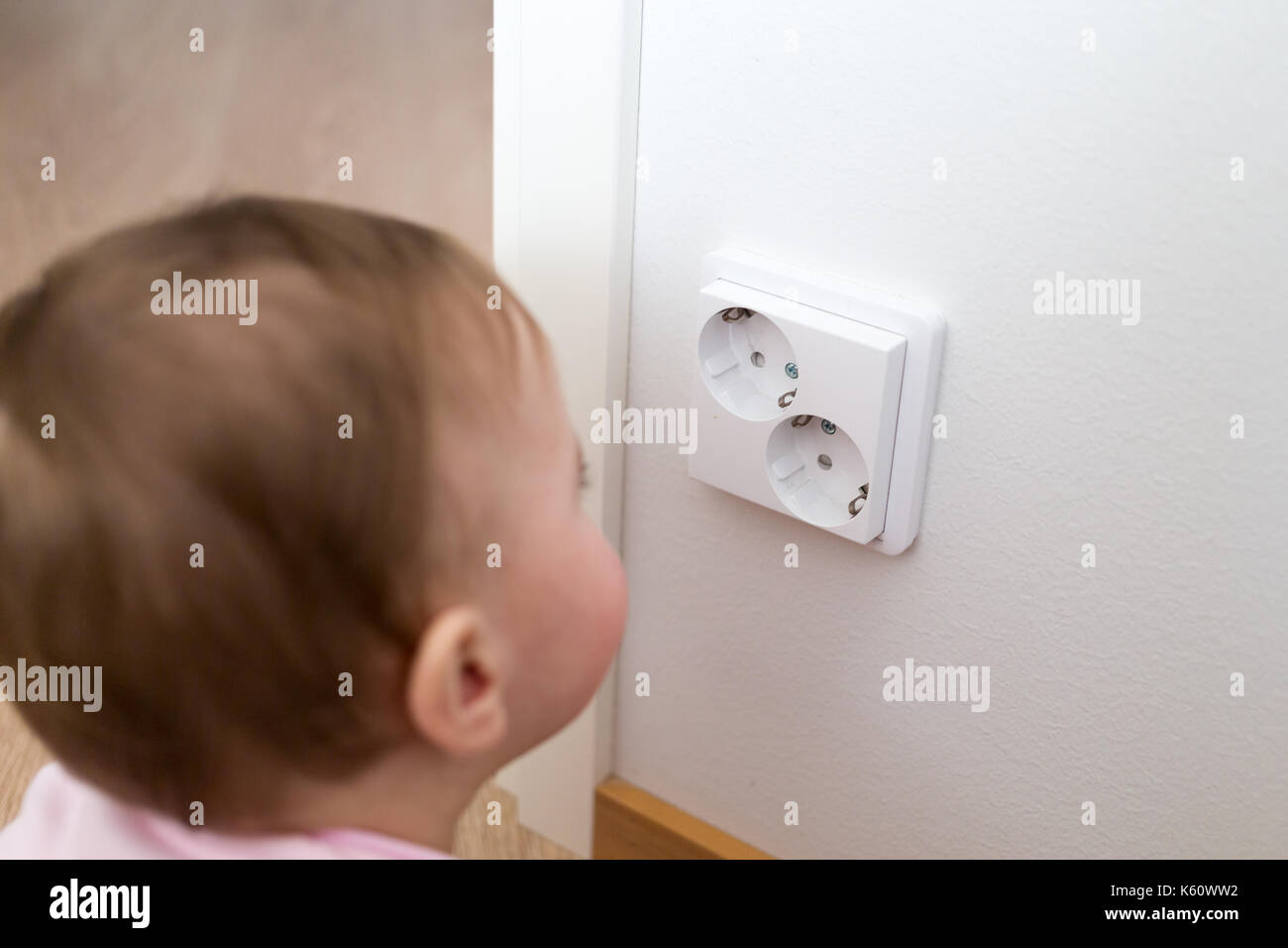 Small child is looking at an electrical outlet at home. Safety of children. Stock Photo